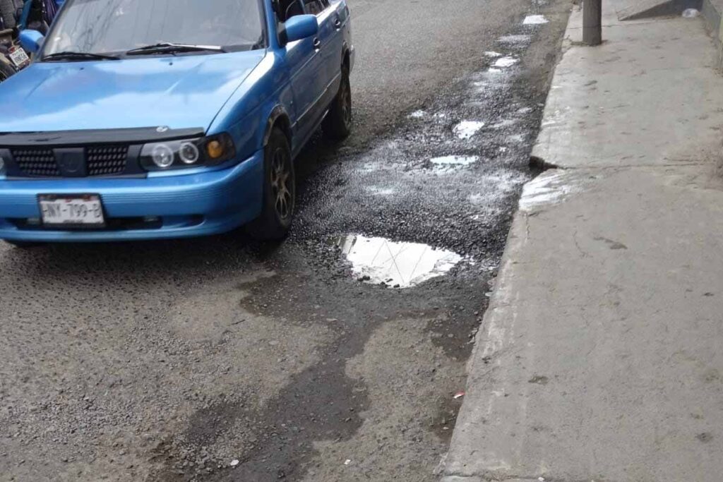 Ciudadanos, comerciantes y el transporte público transitan a diario por la calle Constitución afectada por baches