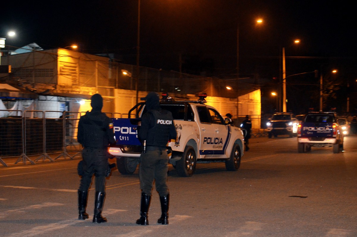 Los oficiales de policía hacen guardia en la entrada de la prisión después de un motín armado que dejó cuatro muertos y docenas de heridos en Machala, Ecuador, el 9 de noviembre de 2025. Al menos 27 reclusos fueron encontrados muertos por asfixia el domingo por la tarde en una prisión del suroeste de Ecuador, horas después de que la policía controlara un motín armado que dejó cuatro muertos y decenas de heridos durante las primeras horas de la mañana. (Foto de Luis SUAREZ / AFP)