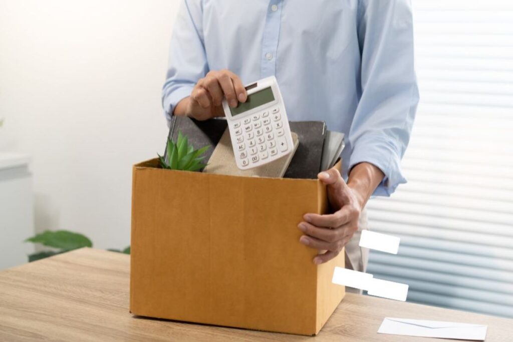 Foto que muestra a una persona guardando sus pertenencias dentro de una caja, entre ellas una calculadora, como símbolo de desempleo o despido laboral