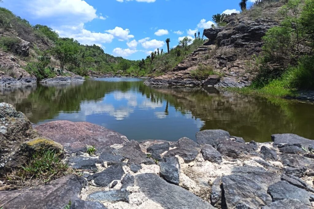 Paisaje de Huichapan en el que aparece un cuerpo de agua rodeado de piedras y vegetación